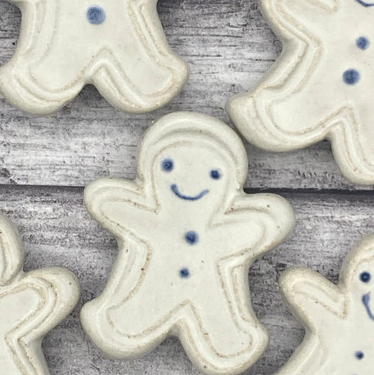 White ceramic gingerbread men with blue details on a wooden surface